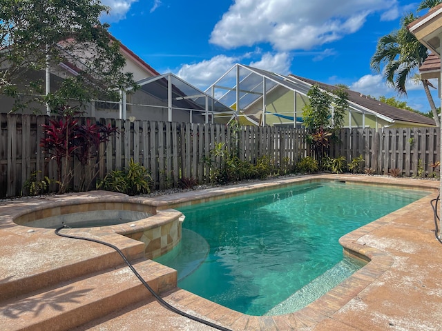 view of pool with a lanai, a fenced backyard, and a pool with connected hot tub