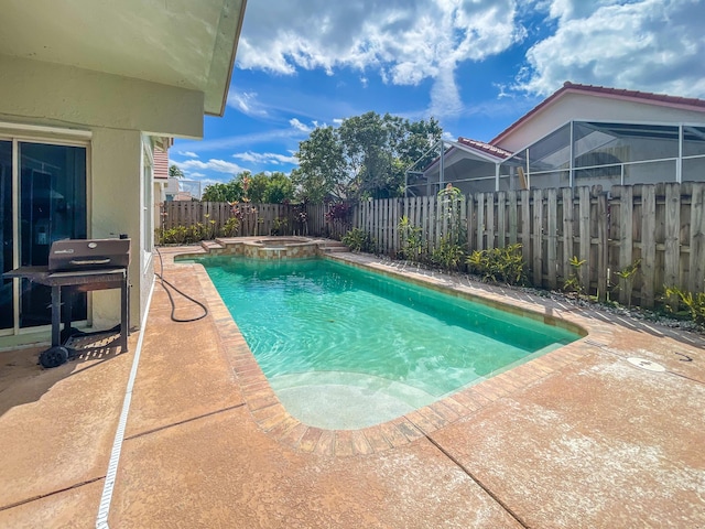 view of pool featuring a patio, glass enclosure, a fenced backyard, a pool with connected hot tub, and grilling area