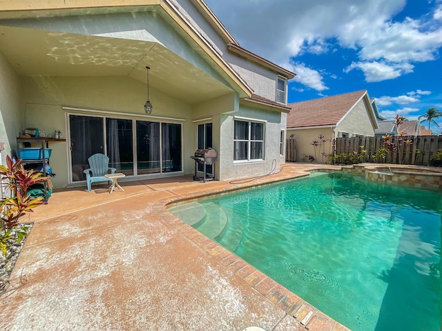 view of swimming pool featuring a pool with connected hot tub, a grill, fence, and a patio