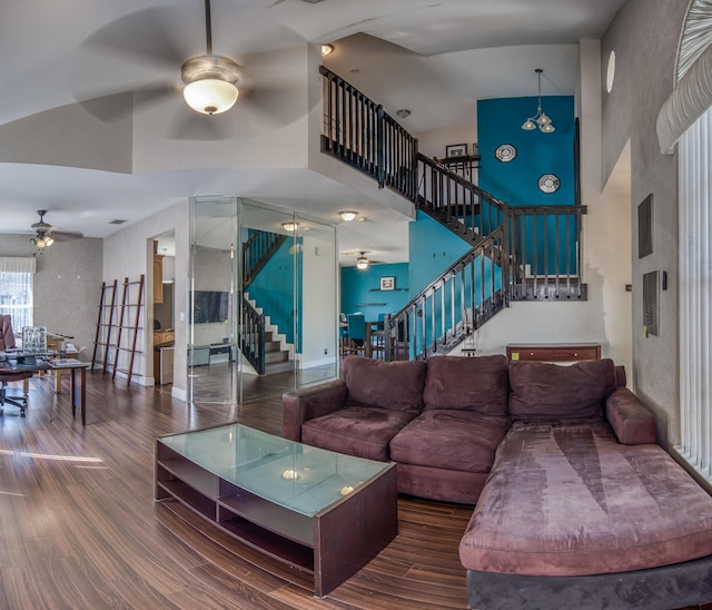 living area with a ceiling fan, stairway, a towering ceiling, and wood finished floors