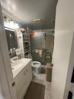 bathroom featuring a shower with shower door, vanity, and toilet