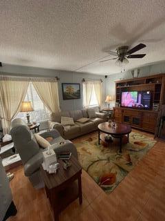 living room with a textured ceiling and ceiling fan