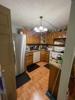 kitchen with a notable chandelier, a textured ceiling, pendant lighting, and white appliances