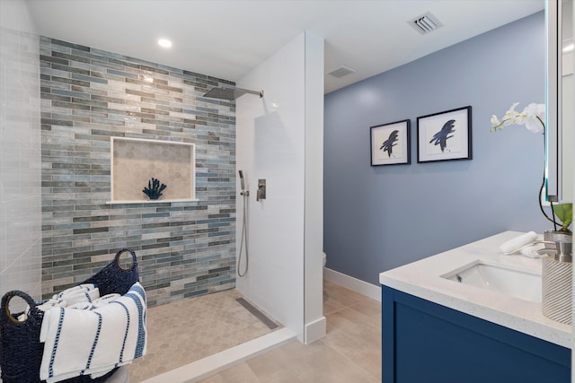 bathroom with vanity, tile patterned flooring, and a tile shower