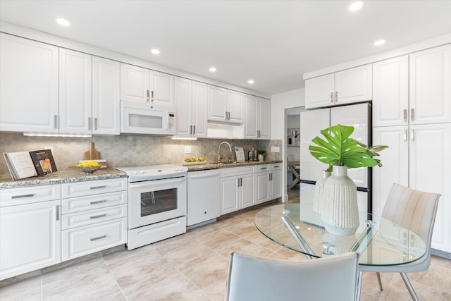 kitchen with backsplash, sink, white appliances, and white cabinetry