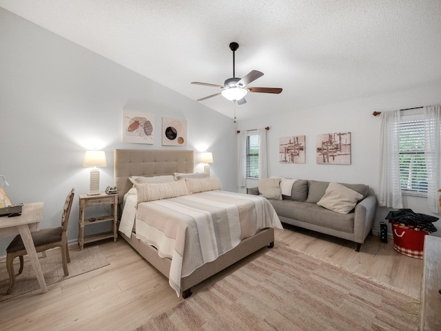 bedroom featuring ceiling fan, light hardwood / wood-style floors, a textured ceiling, and lofted ceiling