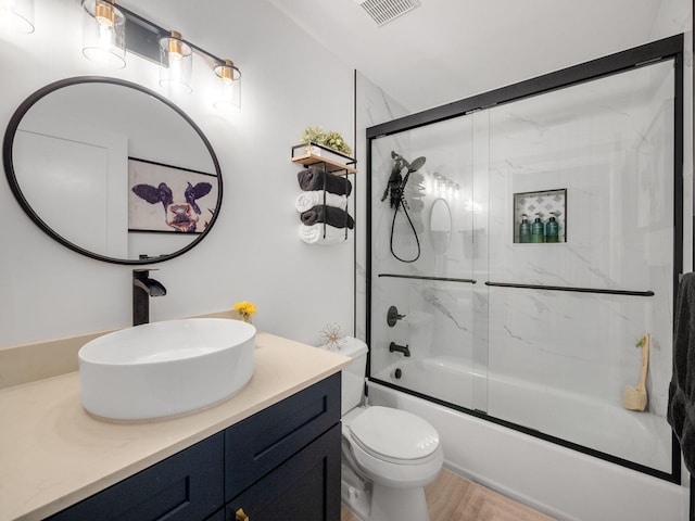 full bathroom featuring hardwood / wood-style flooring, bath / shower combo with glass door, toilet, and vanity