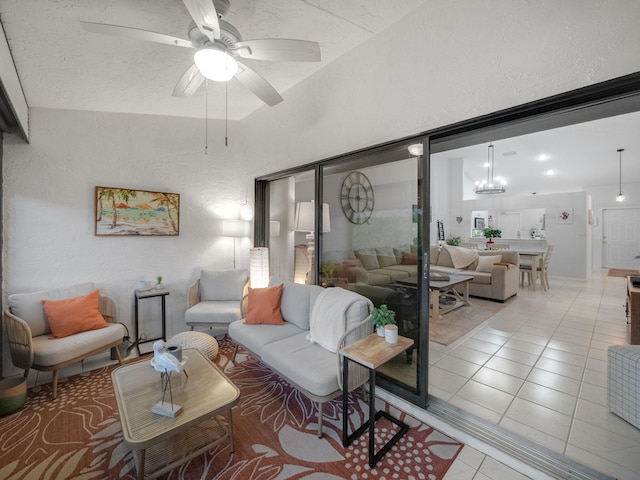 tiled living room with ceiling fan with notable chandelier