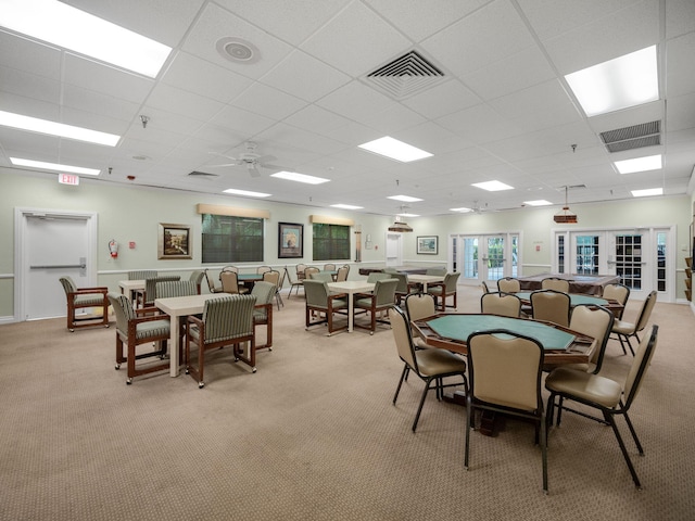 dining space featuring ceiling fan, light colored carpet, a paneled ceiling, and french doors