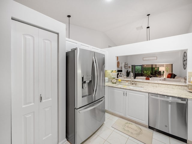 kitchen featuring appliances with stainless steel finishes, white cabinetry, sink, light stone counters, and lofted ceiling