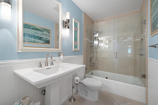 bathroom with toilet, shower / bath combination with glass door, and tile patterned flooring