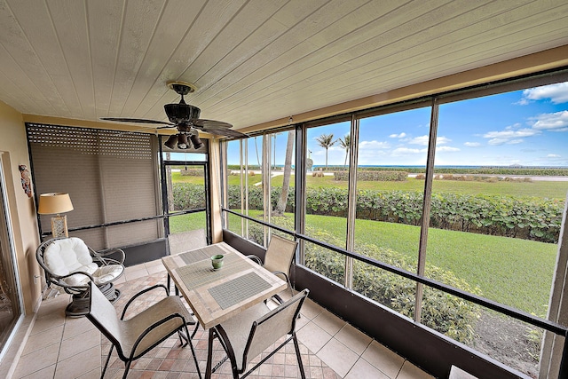 unfurnished sunroom featuring wood ceiling, ceiling fan, plenty of natural light, and a rural view