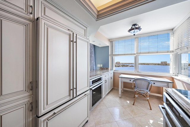 kitchen with a wealth of natural light, a water view, ornamental molding, and stainless steel oven