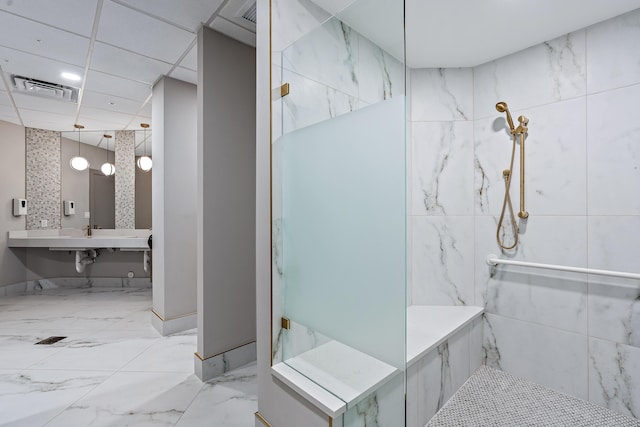 bathroom with tiled shower and a drop ceiling