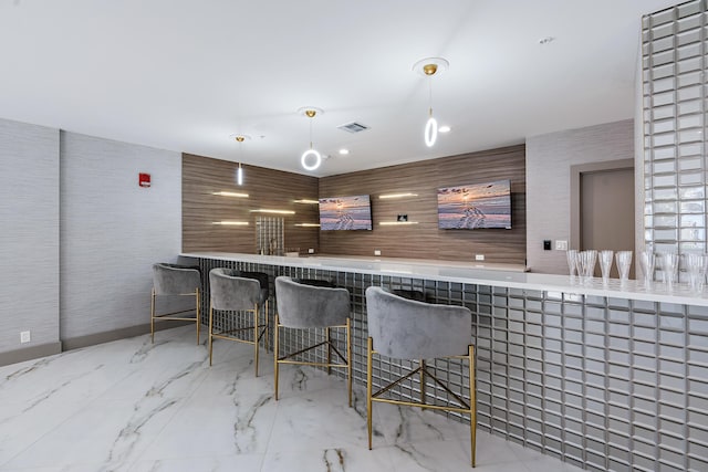 bar with marble finish floor, indoor wet bar, hanging light fixtures, and visible vents