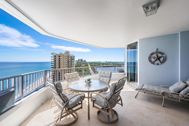 balcony with outdoor dining space and a water view