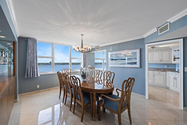 dining space with a notable chandelier, crown molding, and a water view