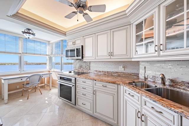 kitchen featuring a water view, a sink, ornamental molding, appliances with stainless steel finishes, and backsplash