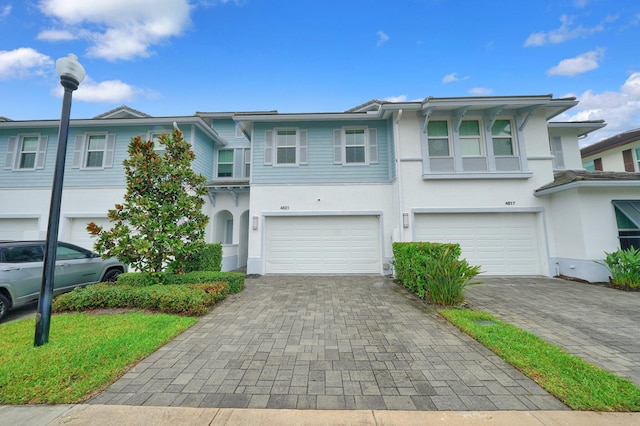 townhome / multi-family property featuring an attached garage, decorative driveway, and stucco siding