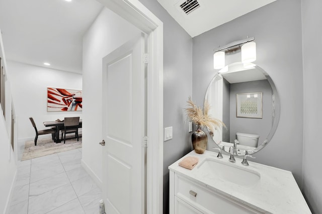 bathroom with toilet, vanity, visible vents, baseboards, and marble finish floor