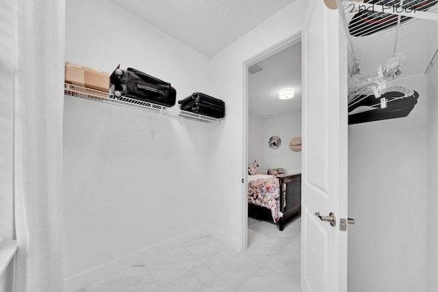 walk in closet with marble finish floor and visible vents