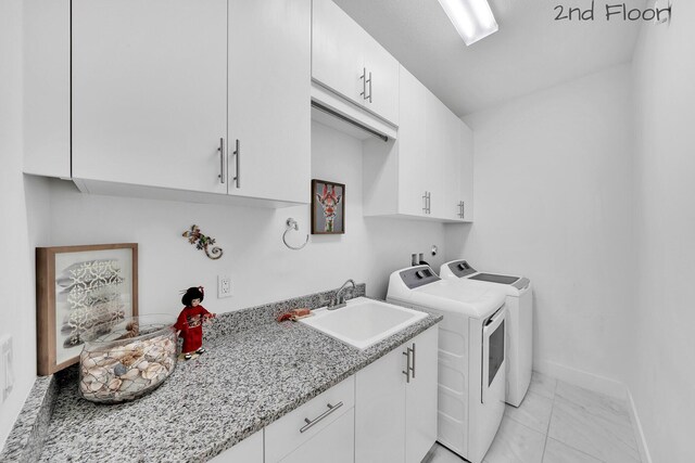 laundry room with cabinet space, baseboards, washer and clothes dryer, and a sink