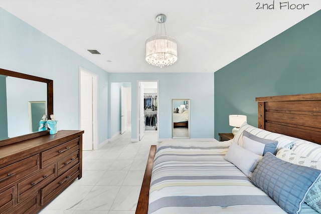 bedroom featuring baseboards, a walk in closet, visible vents, and a notable chandelier