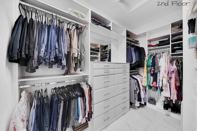 spacious closet featuring marble finish floor and attic access