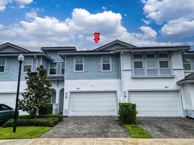 multi unit property with decorative driveway, an attached garage, and stucco siding