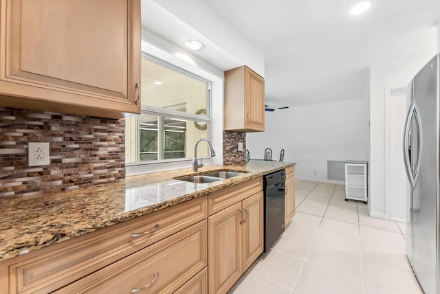 kitchen with black dishwasher, decorative backsplash, sink, stainless steel refrigerator, and light stone counters