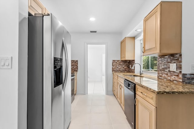 kitchen with light brown cabinets, stainless steel appliances, sink, light stone counters, and light tile patterned floors