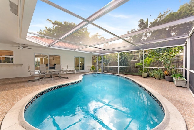 view of swimming pool featuring glass enclosure, a patio area, and ceiling fan