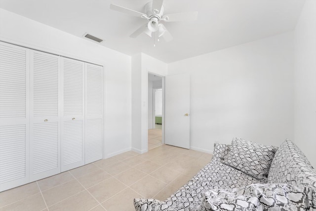 bedroom featuring ceiling fan, light tile patterned flooring, and a closet