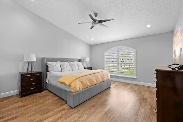 bedroom with ceiling fan, a textured ceiling, lofted ceiling, and light wood-type flooring