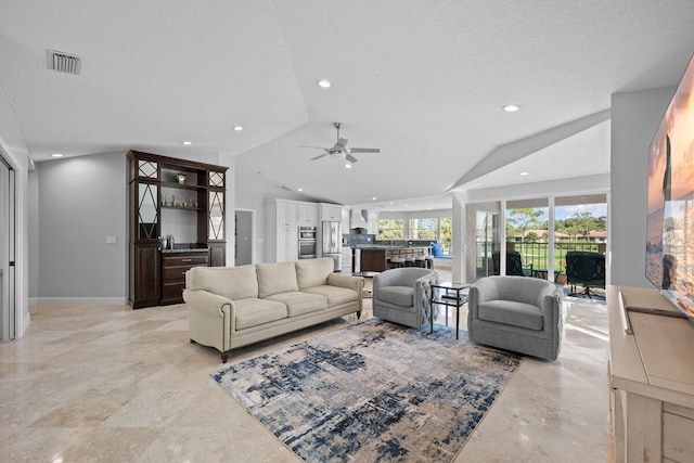 living room featuring ceiling fan, vaulted ceiling, and a textured ceiling