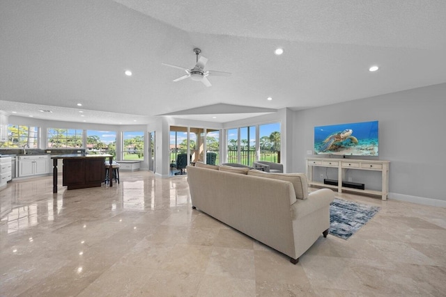 living room featuring ceiling fan, a healthy amount of sunlight, vaulted ceiling, and a textured ceiling