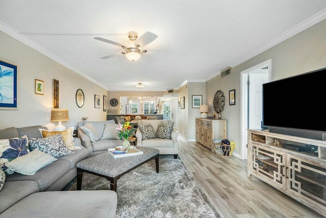 living room featuring light hardwood / wood-style floors, a textured ceiling, ornamental molding, and ceiling fan