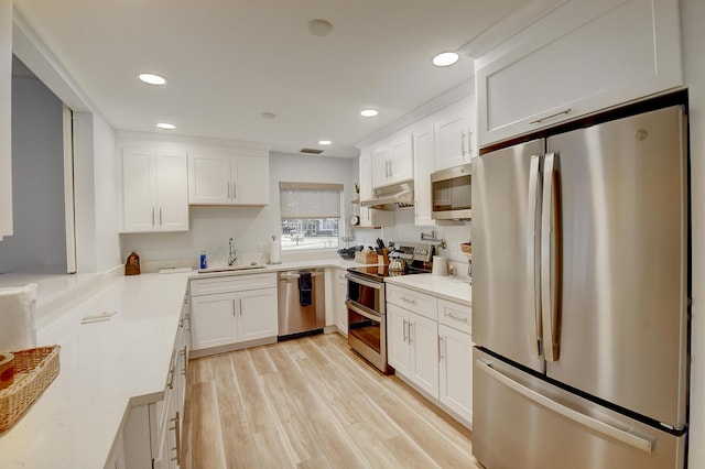 kitchen with light wood-type flooring, stainless steel appliances, white cabinets, and sink