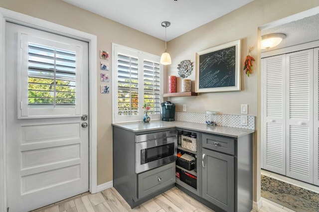 kitchen featuring light wood-type flooring, decorative light fixtures, tasteful backsplash, and gray cabinets