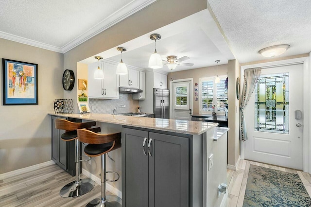 kitchen with white cabinets, kitchen peninsula, a breakfast bar area, and high end fridge