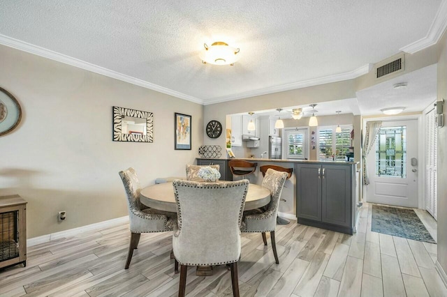 dining room with a textured ceiling, ornamental molding, and light hardwood / wood-style floors