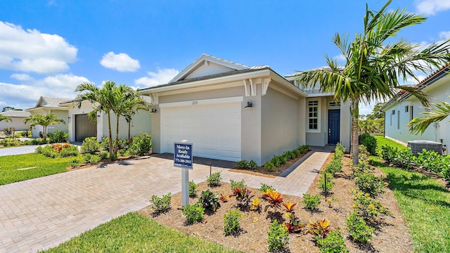 205 SE Via Sangro, Port Saint Lucie, FL 34952 - single story home featuring a garage, decorative driveway, stucco siding, and central air condition unit