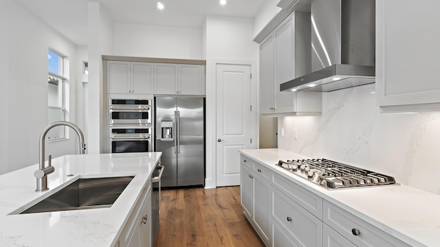 205 SE Via Sangro, Port Saint Lucie, FL 34952 - kitchen featuring stainless steel appliances, wall chimney exhaust hood, a sink, decorative backsplash, and wood finished floors
