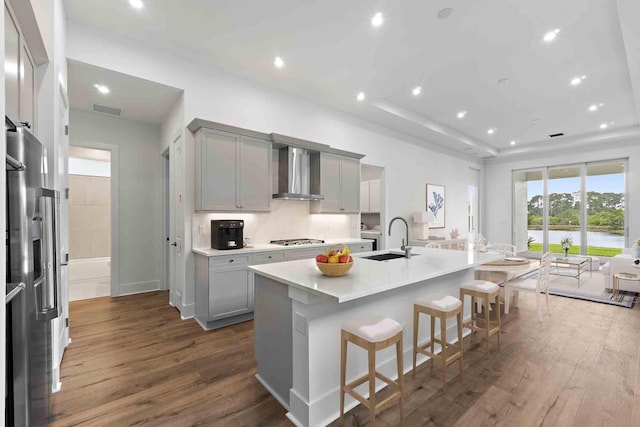 205 SE Via Sangro, Port Saint Lucie, FL 34952 - kitchen featuring wall chimney exhaust hood, a sink, dark wood finished floors, a tray ceiling, and recessed lighting