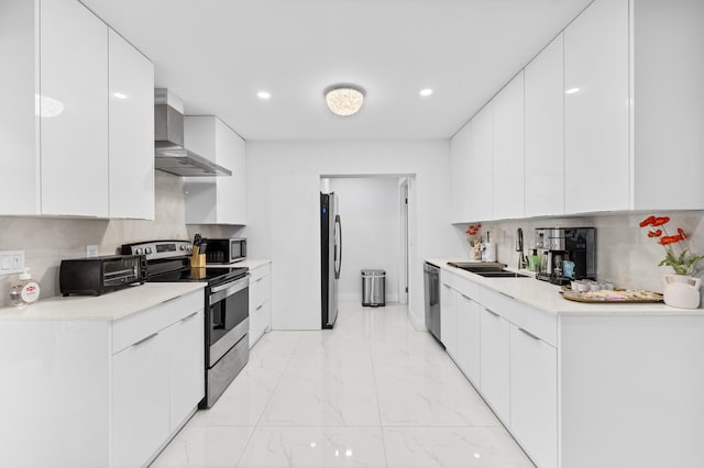 kitchen with stainless steel appliances, sink, white cabinets, and wall chimney exhaust hood