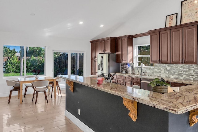 kitchen featuring sink, vaulted ceiling, light tile patterned floors, stainless steel appliances, and decorative backsplash