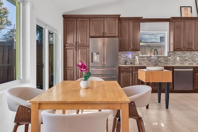 kitchen with sink, decorative backsplash, stainless steel fridge, and dark brown cabinets