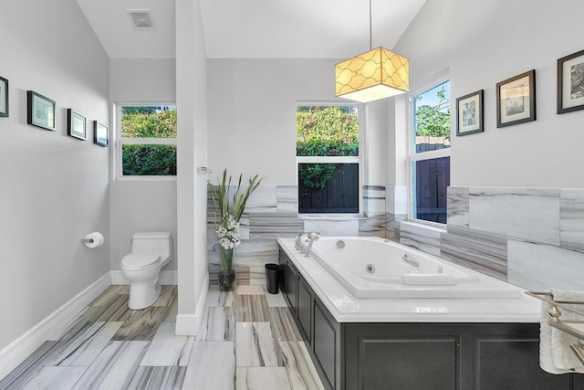 bathroom featuring a bathing tub, vaulted ceiling, and toilet