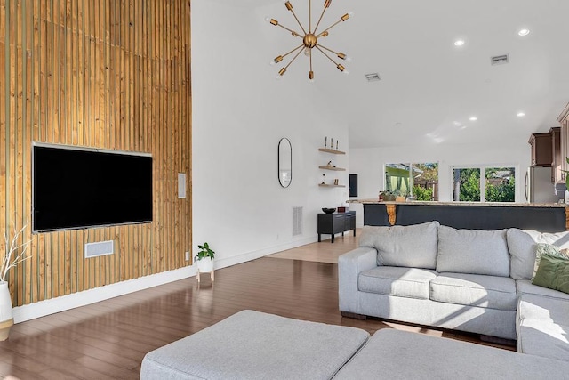 living room featuring an inviting chandelier, wooden walls, and dark hardwood / wood-style flooring