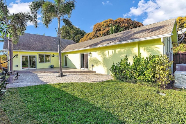 back of property with a patio, central AC, and a lawn